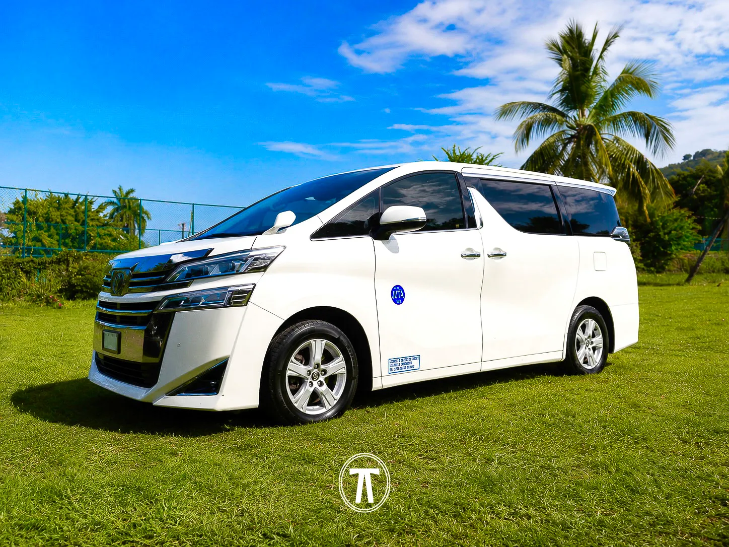 White passenger van with JUTA certification sticker, parked on grass with palm trees in Jamaica