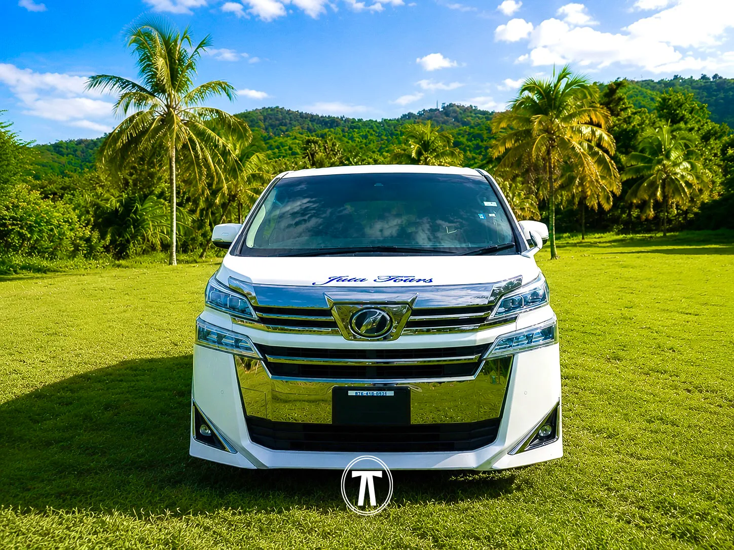 White passenger van with Juta Tours branding, parked in a tropical Jamaican setting